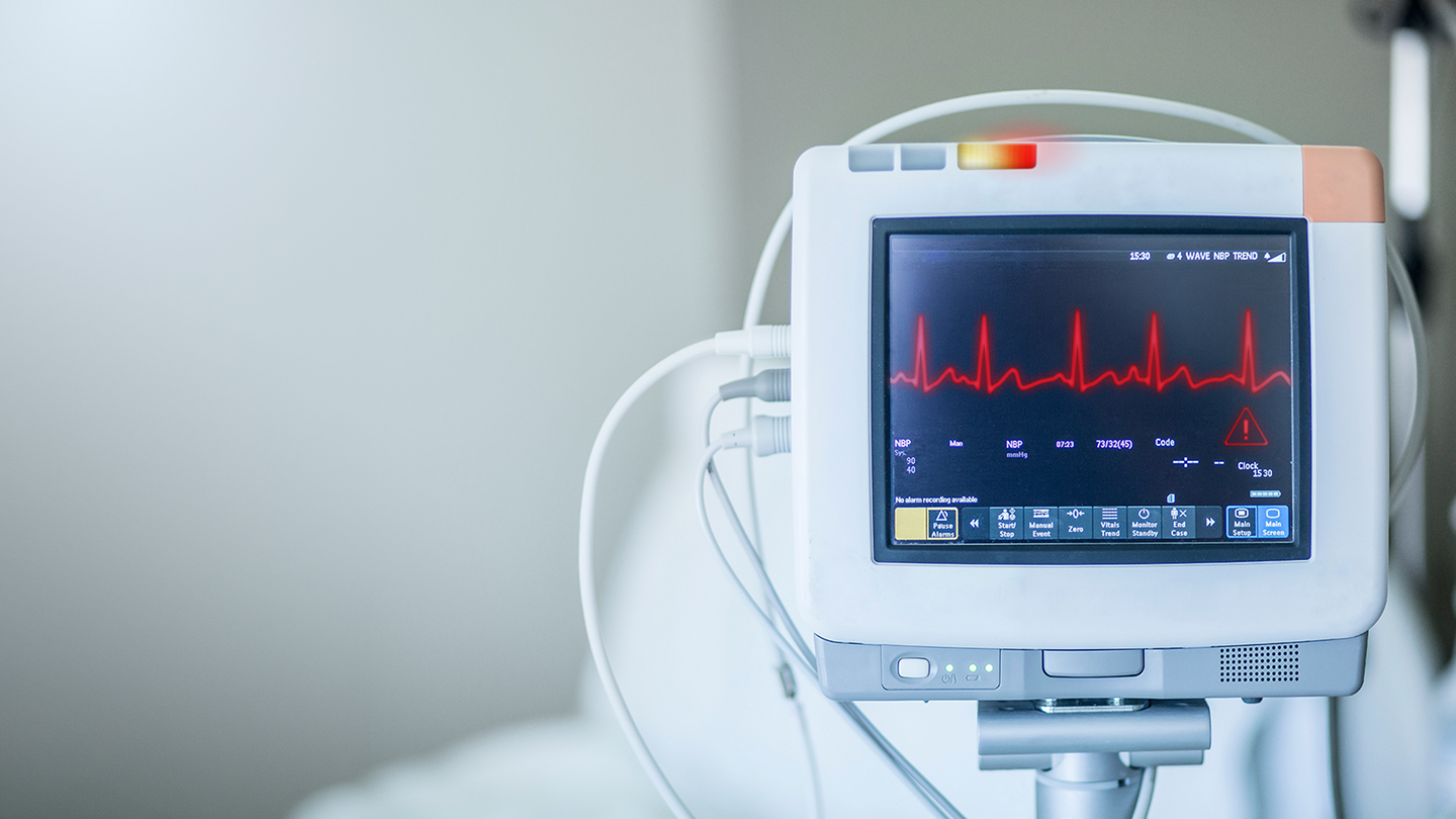 An EKG machine with a red line and exclamation mark on it
